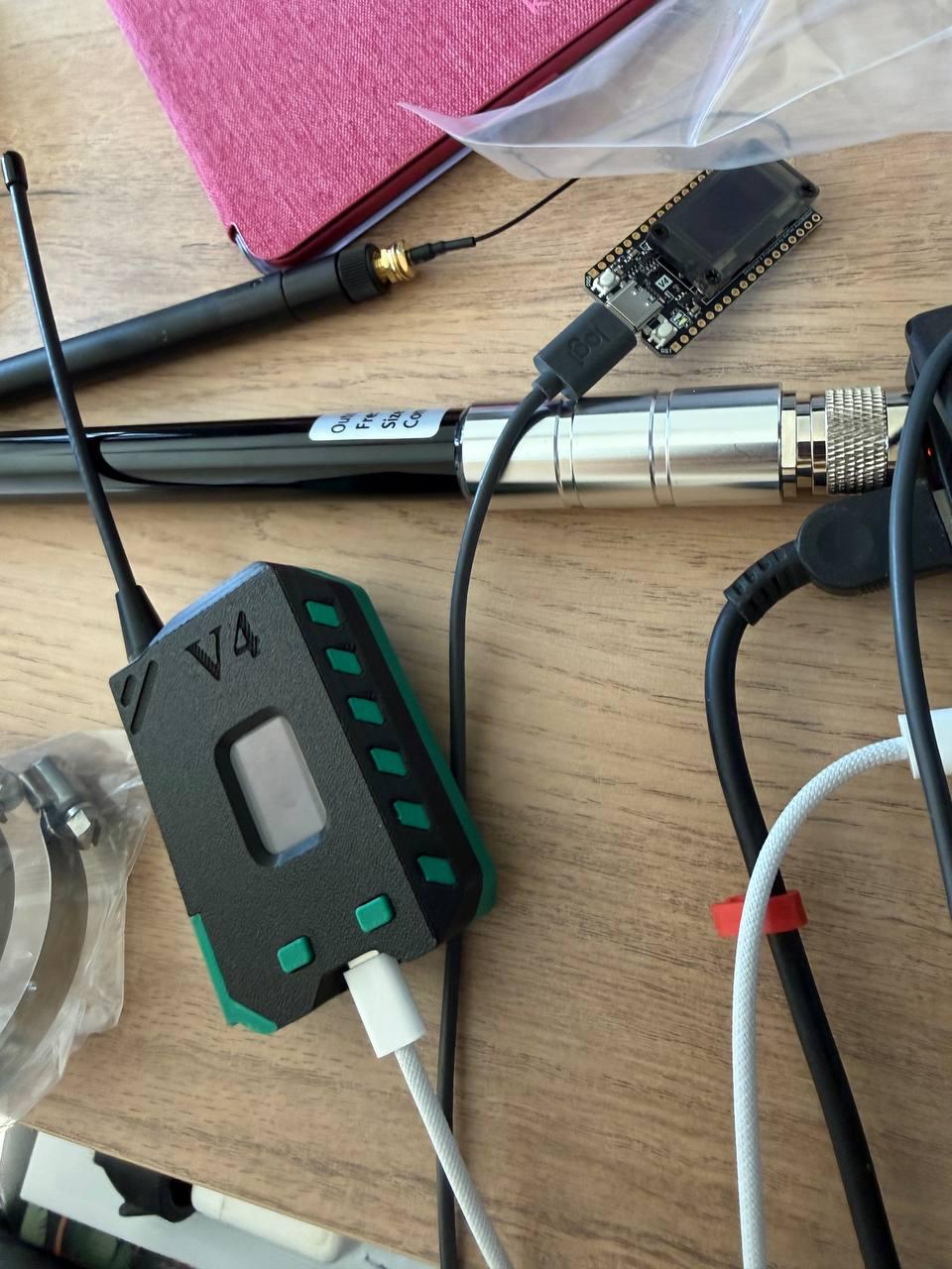 One LoRa heltec v4 device in case and another in board while testing, also visible big antenna disconnected and pink kindle